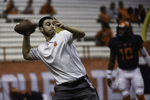 Jake Warren, a student manager on the football team, takes part in pre-game warmups. The managers can work for up to 14 hours on a game day and are assigned to aid a specific position group, such as running backs or quarterbacks.                          spencer bodian staff photographer