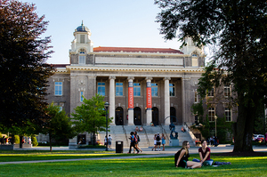 Carnegie Library at Syracuse University with students sitting and walking around.
